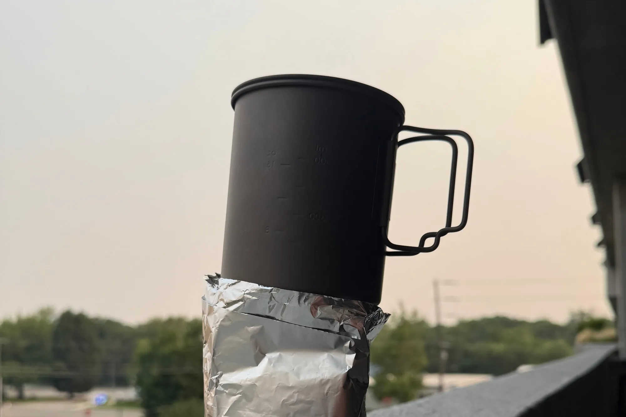 A tinfoil windscreen wrapped around the canister and BRS stove on a ledge