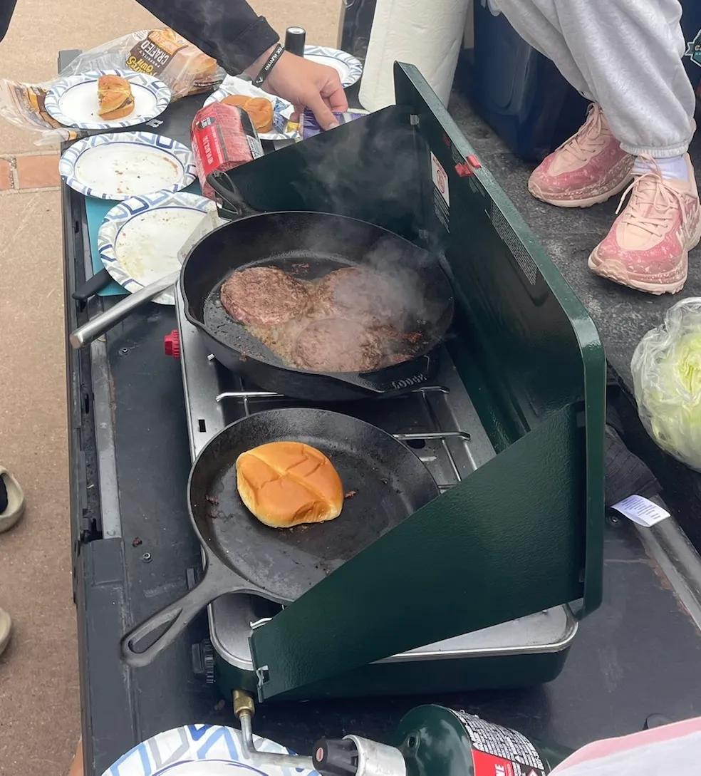 Burgers going in the cast iron on the tailgate, buns toasting on the second burner