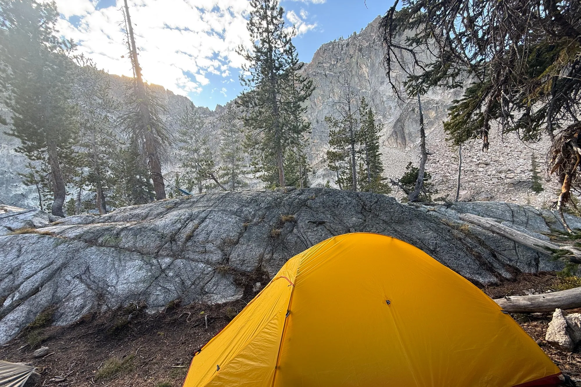 The tent pitched in early morning light below a Sawtooth peak